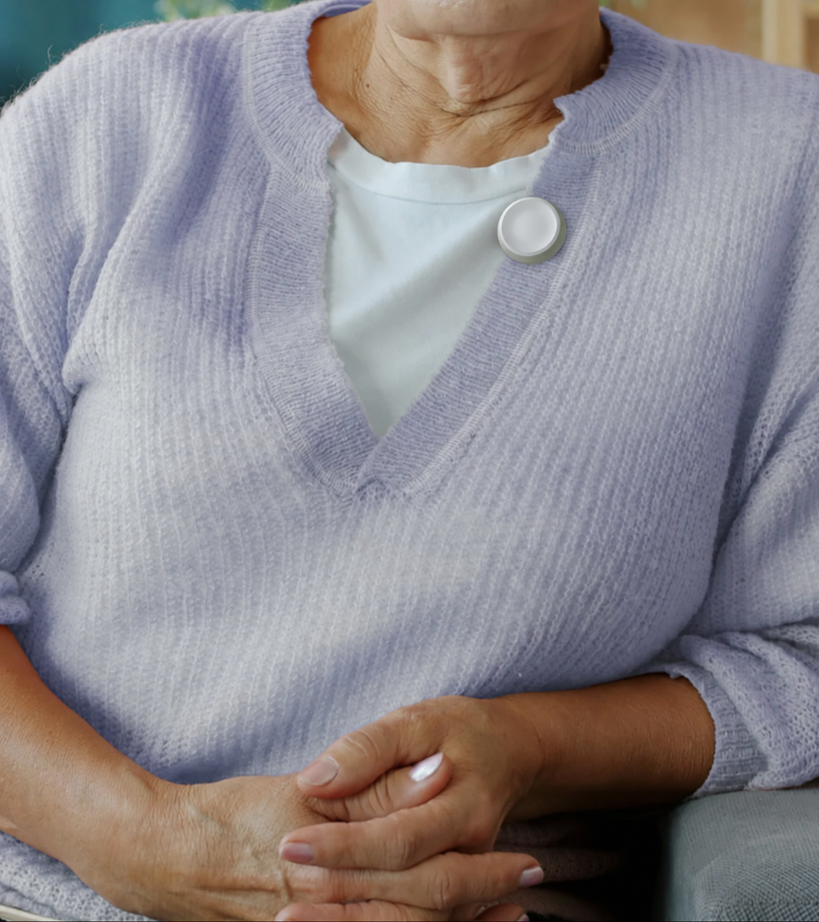 Concept visualization of a circular help button clipped to a resident’s cardigan