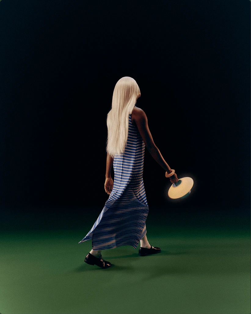 A person walking across a dark room carrying a glowing Gantri Eave lamp