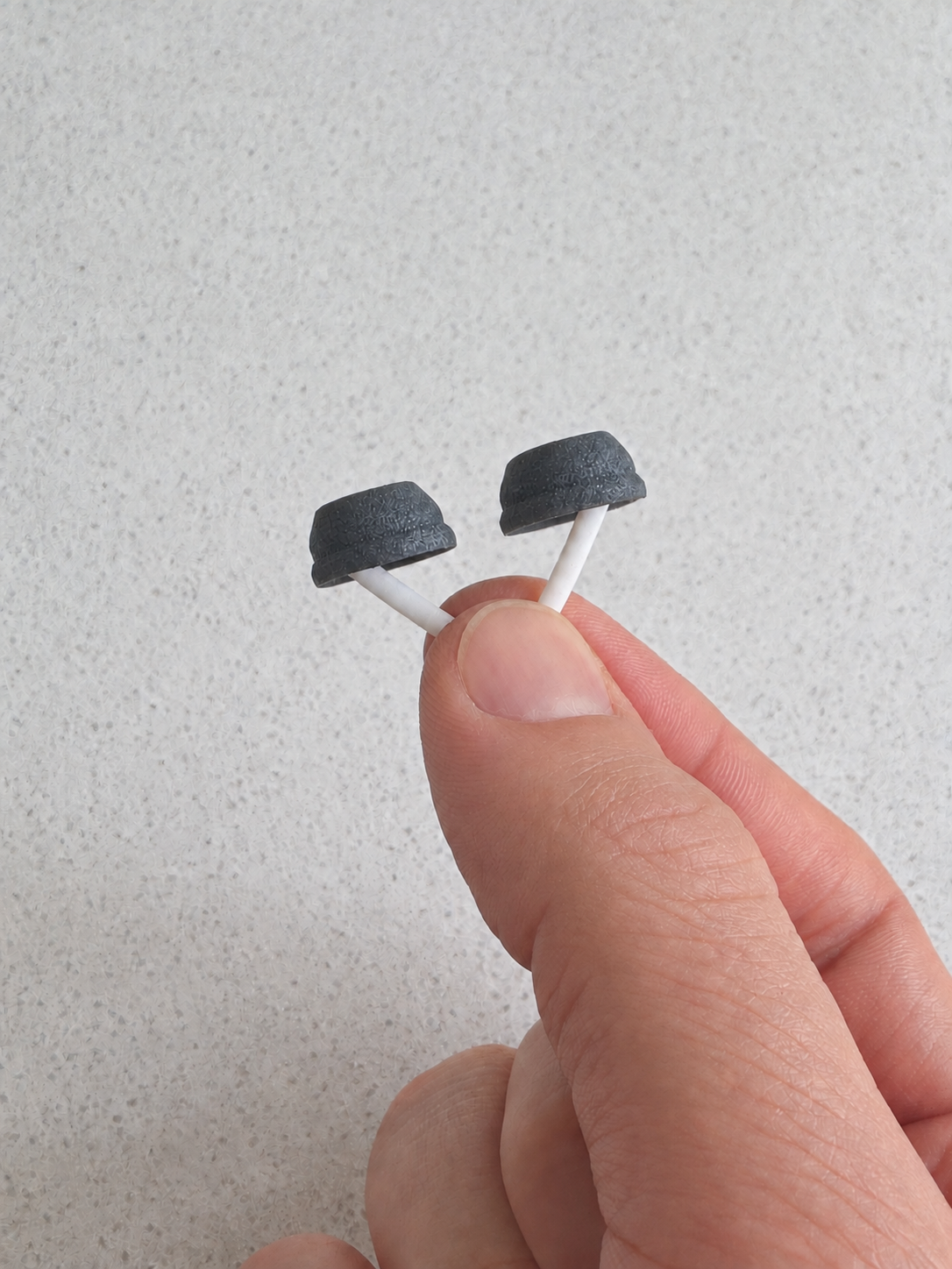A small wearable prototype held at its center between thumb and finger